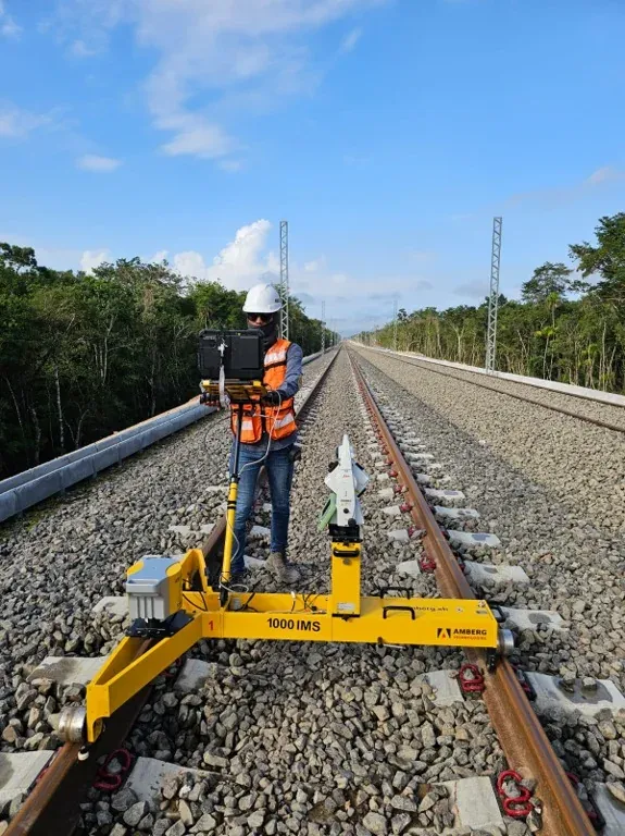 Operador con carro de medición de vía Amberg 1000 IMS sobre la vía recta, con estación total y tableta de control