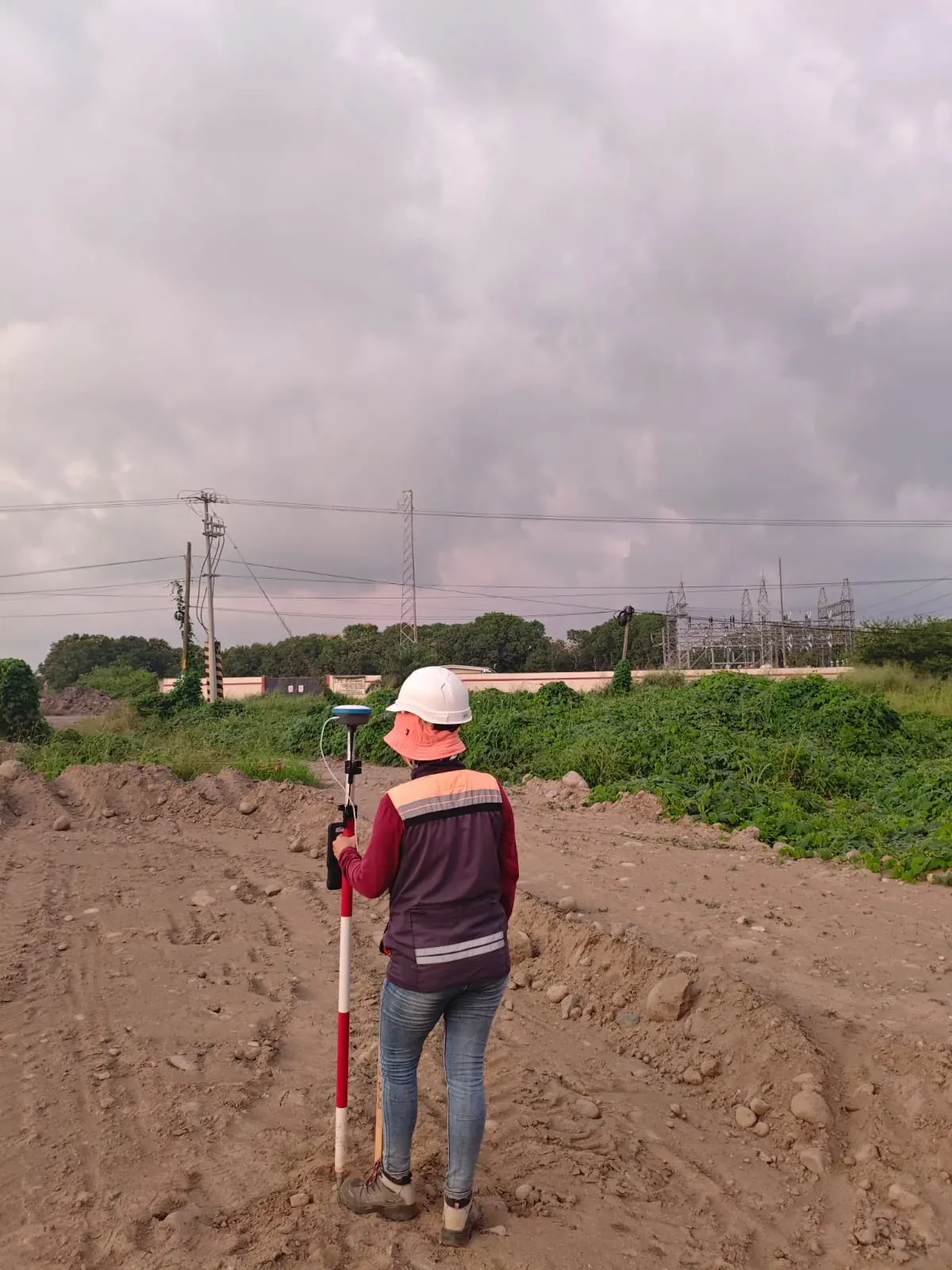Topógrafa de espaldas con bastón en terracería