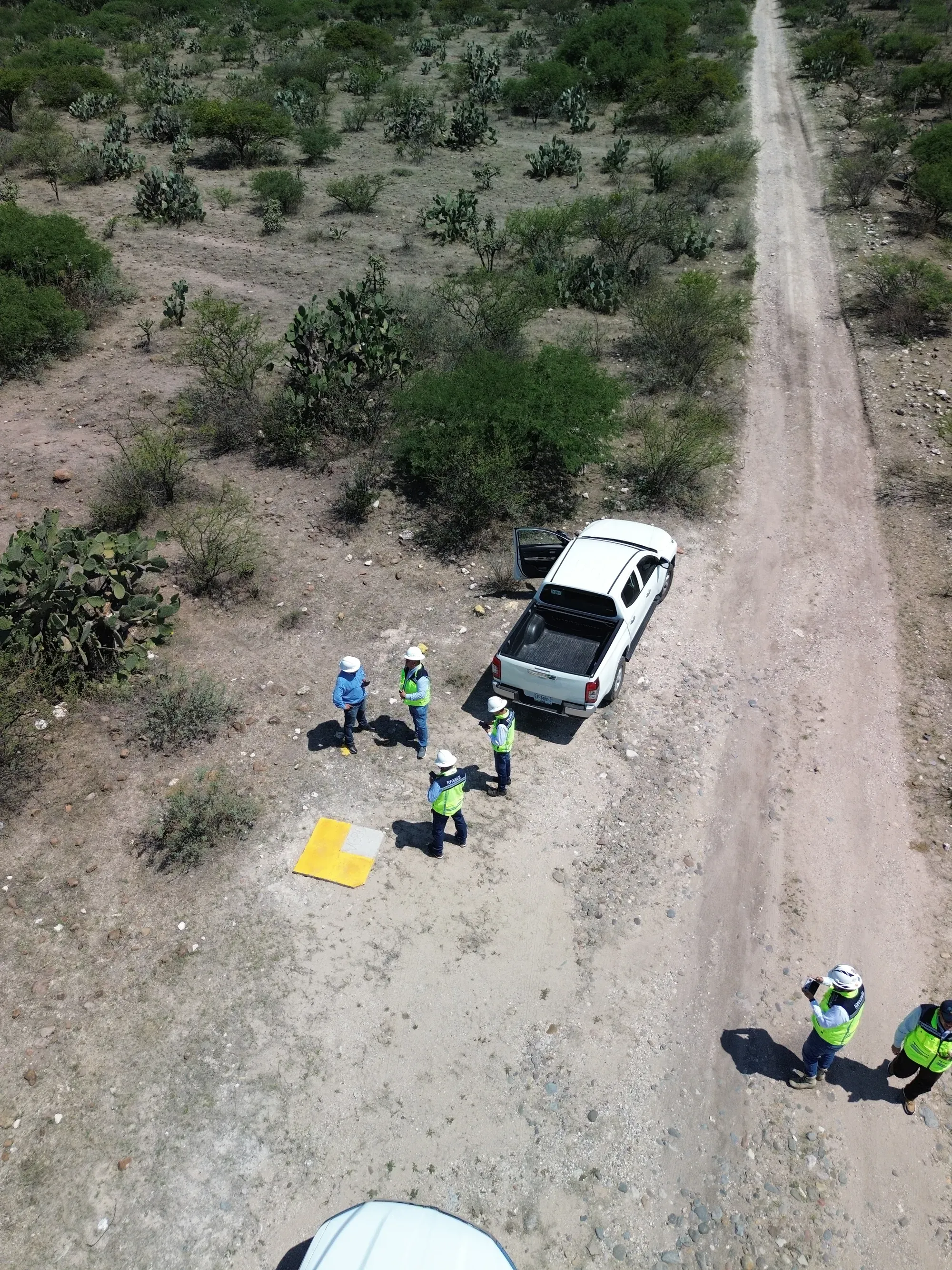 Cuadrilla de topografía y camionetas en camino de terracería, vista desde dron
