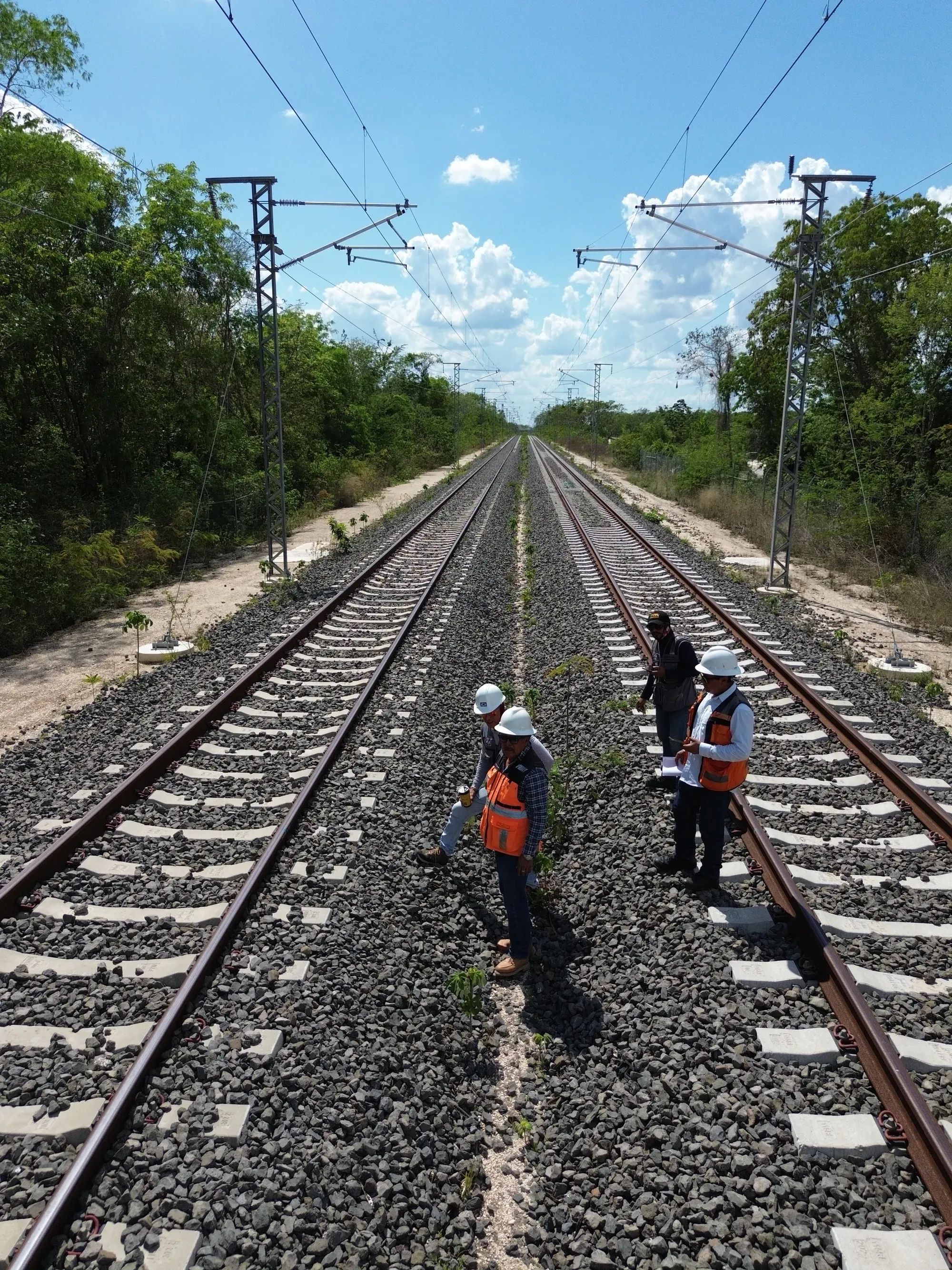 Brigada sobre la vía electrificada, desde dron, con la vía hacia el horizonte