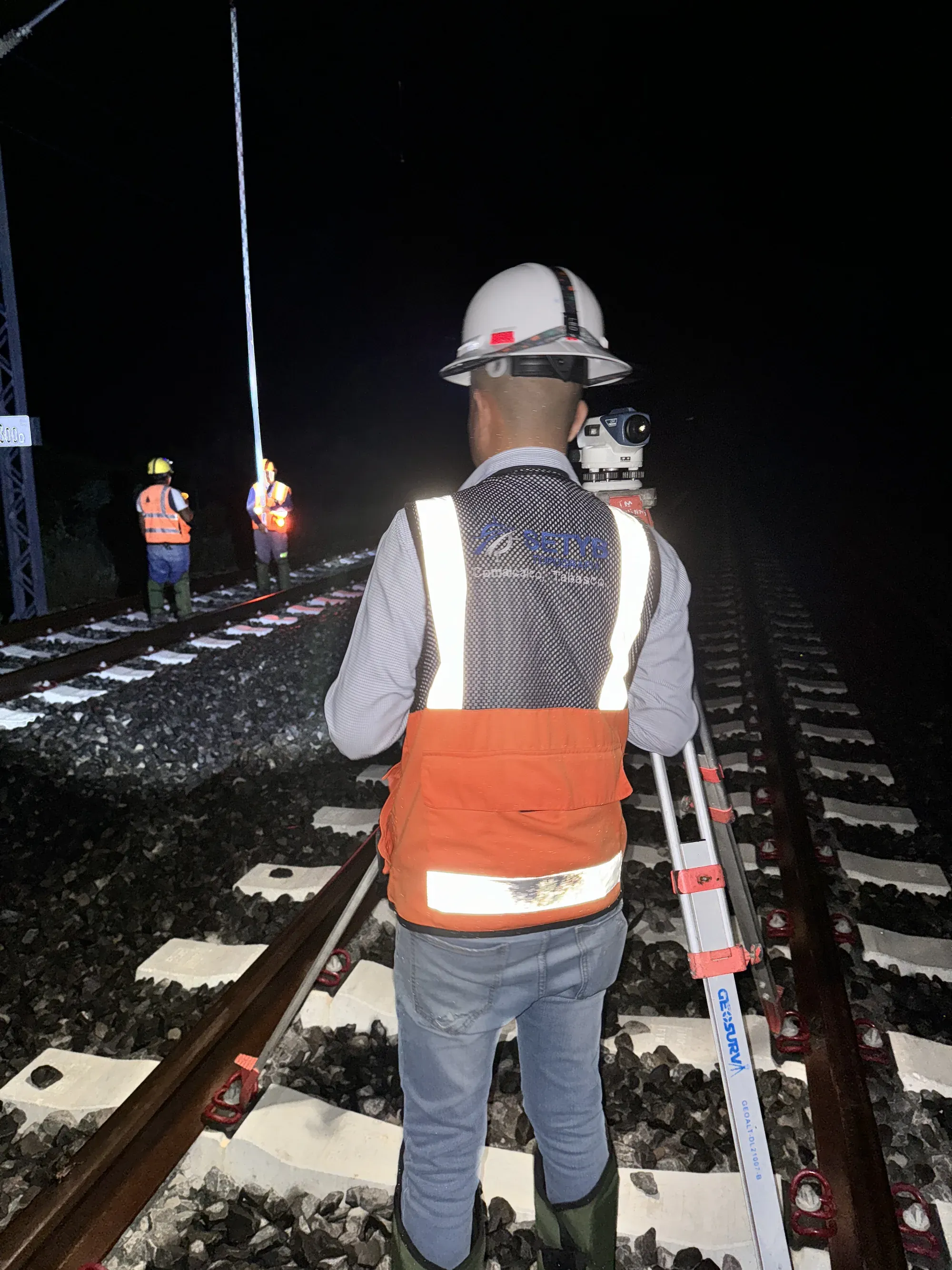 Topógrafo sobre la vía durante una ventana nocturna de trabajo