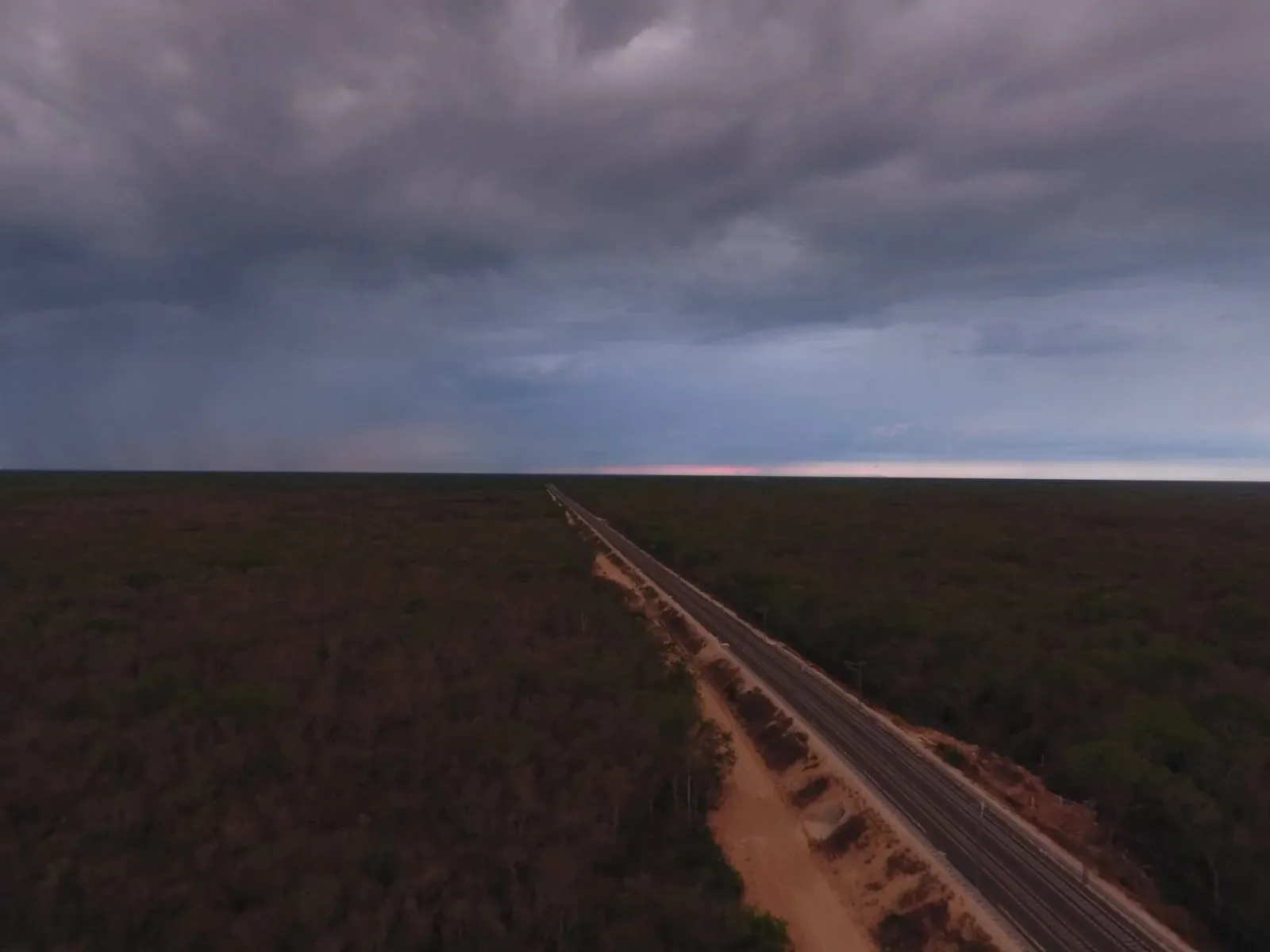 Vía del Tren Maya recta hacia el horizonte al atardecer, entre la selva