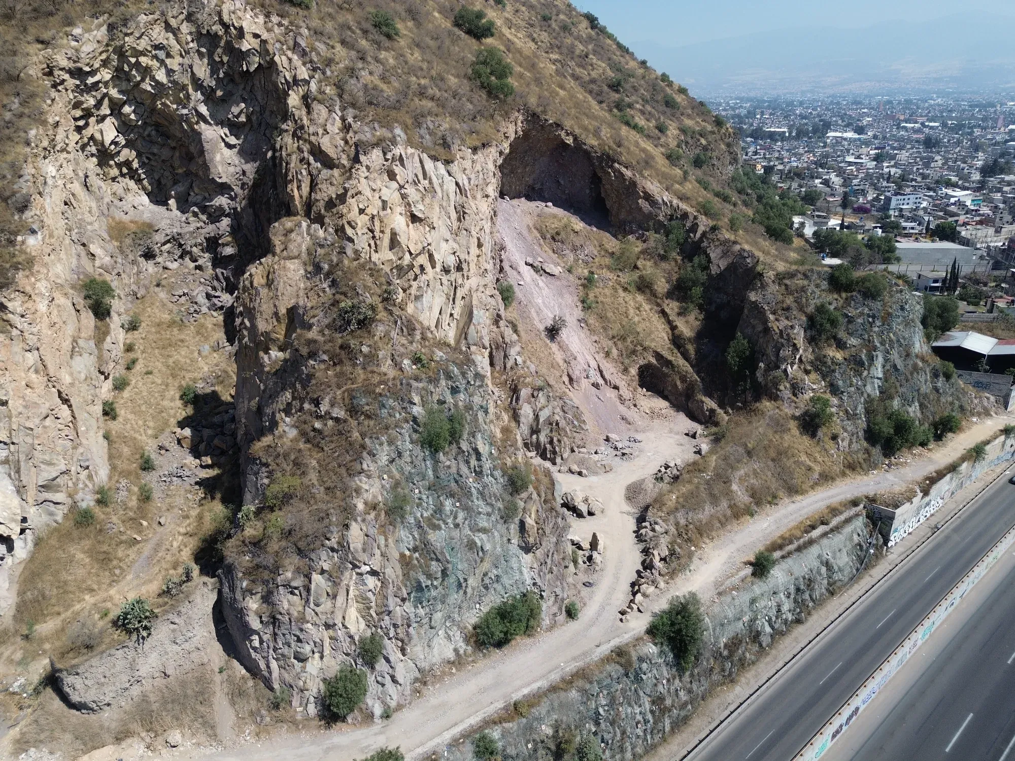 Talud rocoso junto a la vialidad con la ciudad al fondo