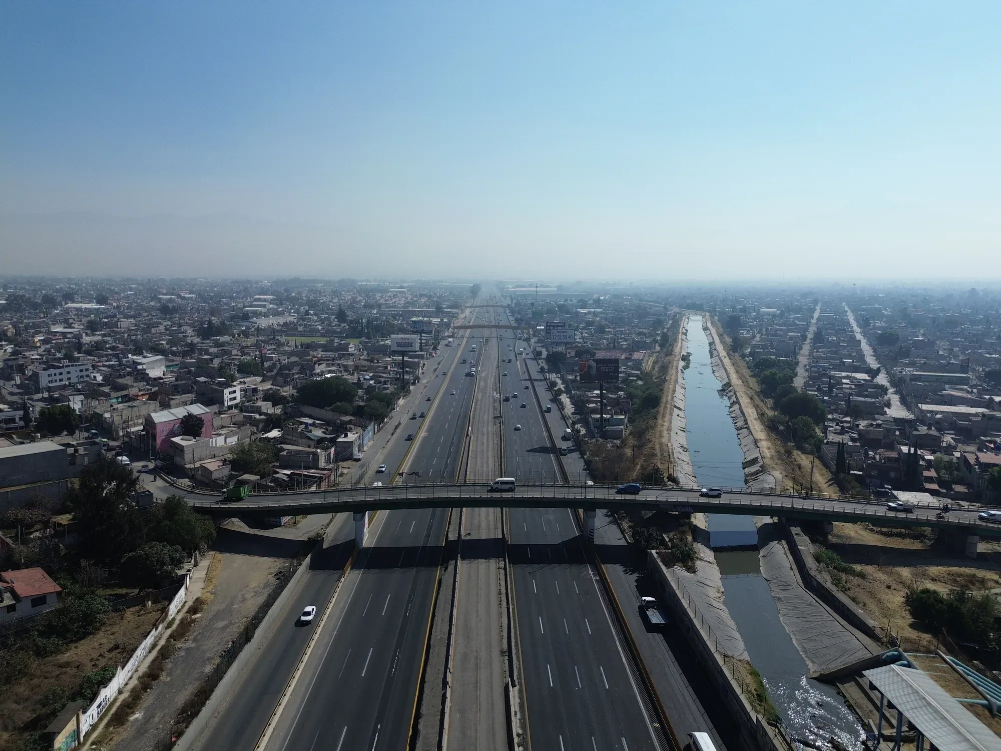 Vialidad recta junto a un canal, vista amplia desde dron